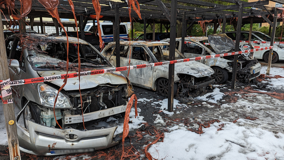 Drei ausgebrannte Autos stehen unter einem Carport © NDR Foto: Loose Christpoh