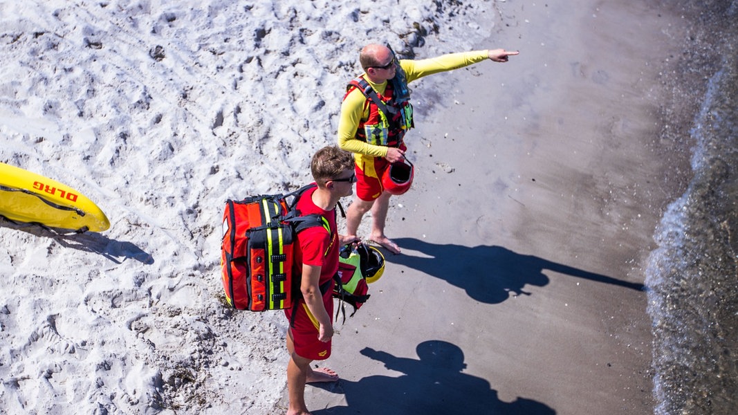 Rettungsschwimmer von der DLRG Wasserrettung stehen am Strand und beobachten die Bädegäste.