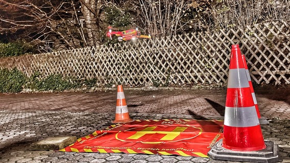 Eine Drohne in roten und gelben DLRG-Farben schwebt über einer Landefläche. © Deutsche Lebens-Rettungs-Gesellschaft Ortsgruppe Graal-Müritz e.V. Foto: André Rieckhoff