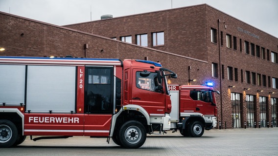 Zwei Feuerwehrfahrzeuge vor einem großen Feuerwehrgebäude. © NDR 