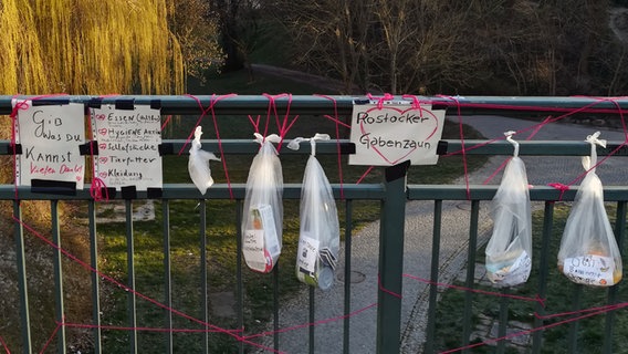 An einem Zaun hängen Spenden für Bedürftige. © NDR Foto: Bernd Kalauch