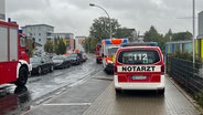 Einsatzwagen von Feuerwehr und Rettungsdienst tummeln sich auf einer Straße vor einer Schule in Neubrandenburg. © NDR Foto: Felix Baenz