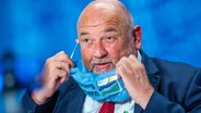 MV-Wirtschaftsminister Harry Glawe (CDU) legt während einer PK einen Mund-Nasenschutz ab. © dpa/picture-alliance Foto: Jens Büttner