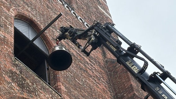 Ein Kran hebt eine Glocke in einen Kirchturm. © Pressestelle der Hansestadt Wismar Foto: Norbert Wiaterek