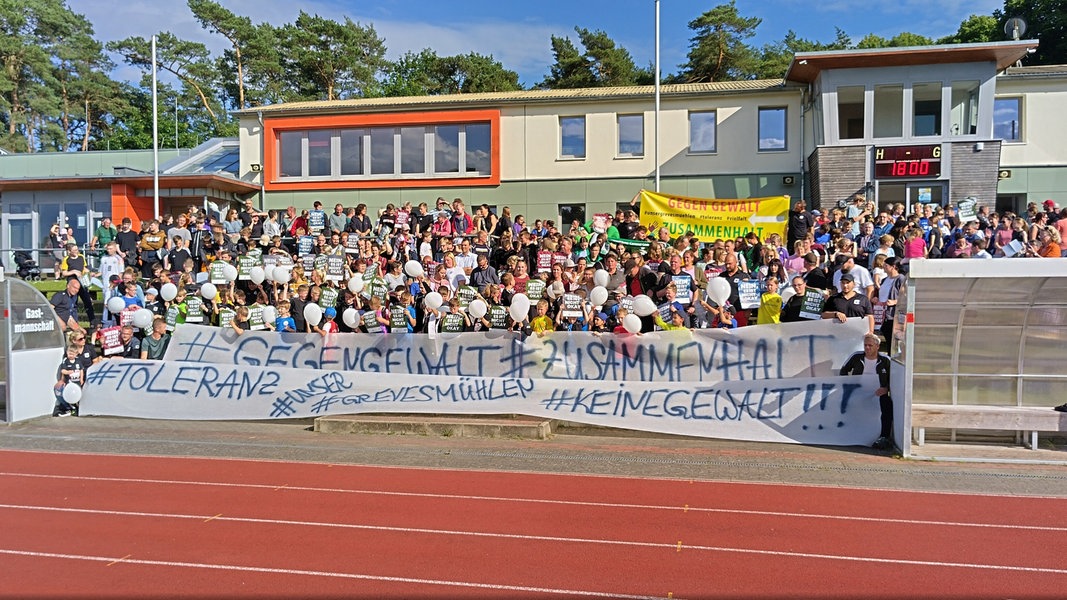 Auf dem Sportplatz in Grevesmühlen protestieren Bürger mit Transpartenten gegen Gewalt.
