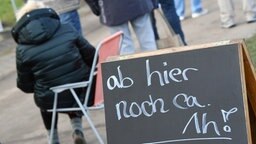 Greifswald: Menschen warten vor dem Impfzentrum des Landkreises Vorpommern-Greifswald an einem Schild mit der Aufschrift 