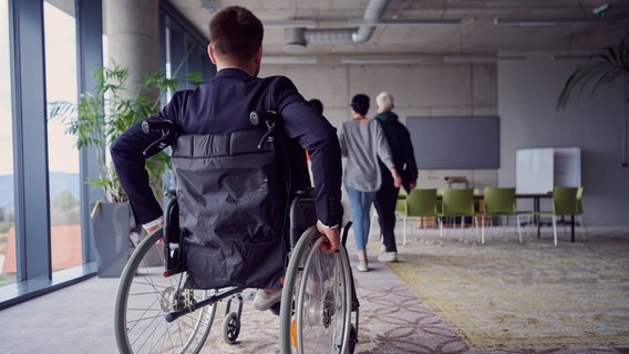 Ein Mann im Rollstuhl in einem Büro © IMAGO / YAY Images 