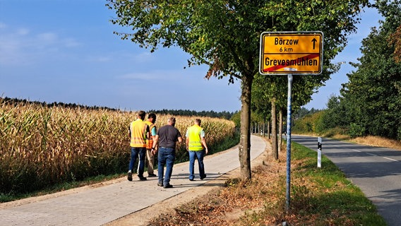 Männer gehen einen Radweg entlang am Ortausgangsschild Grevesmühlen vorbei © Stadt Grevesmühlen 