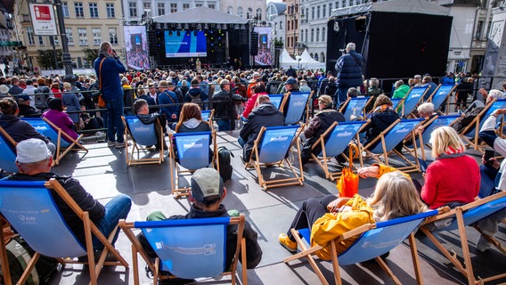 Besucher sitzen auf dem Marktplatz bei der Eröffnung der Feierlichkeiten zum Tag der Deutschen Einheit. © NDR Foto: Jens Büttner