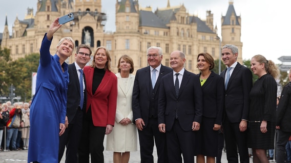 Manuela Schwesig (SPD), Bundesratspräsidentin, macht von sich und ihrem Ehemann Stefan, Bärbel Bas, Bundestagspräsidentin, Elke Büdenbender, Bundespräsident Frank-Walter Steinmeier, Bundeskanzler Olaf Scholz (SPD), Britta Ernst, Bundesverfassungsgerichtspräsident Stephan Harbarth und seine Ehefrau Juliane nach dem Festakt im Mecklenburgischen Staatstheater vor dem Schweriner Schloss ein Selfie. Im Rahmen der Bundesratspräsidentschaft richtet Schwerin unter dem Motto "Vereint Segel setzen" die zentralen Feierlichkeiten zum Tag der Deutschen Einheit aus. © dpa/Jens Büttner Foto: Jens Büttner