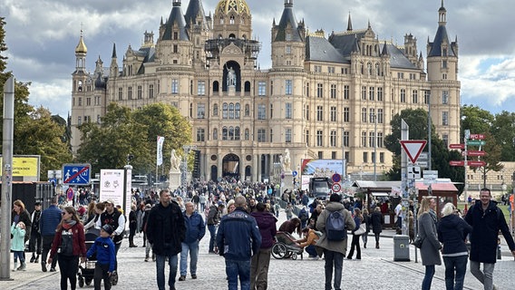 Besucher schlendern vor dem Schweriner Schloss auf der Straße. © NDR Foto: Jan Baumgart