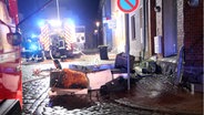 Feuerwehrautos vor einem Haus in dem ein Brand gelöscht wurde. Verkohlte Möbel auf der Straße. © Michael-Günther Bölsche Foto: Michael-Günther Bölsche