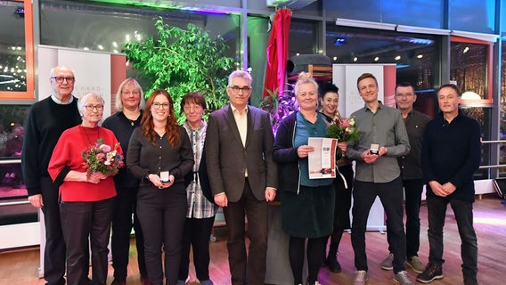 Eine Gruppe Menschen steht zusammen mit einer Urkunde, Blumen und einer Medaille in den Händen © Celine Schmock 