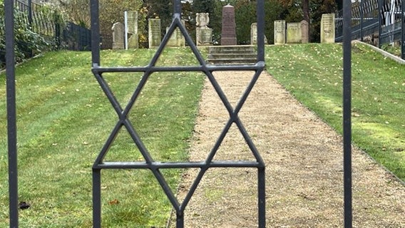 Blick auf Grabsteine des jüdischen Friedhofes in Neubukow durch Metallzaun mit Davidstern © NDR Foto: Juern-Jakob Gericke