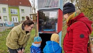 Zwei Erwachsene und zwei Kinder stehen vor einem Regal mit Büchern © NDR/ Janet Lindemann 