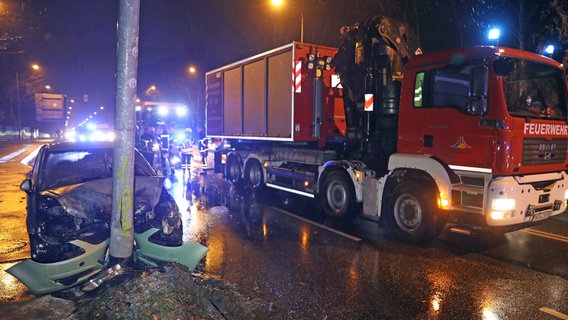 Ein ausgebranntes Auto klemmt frontal an einem Laternenmast, daneben auf der Straße steht ein Feuerwehrauto © Stefam Tretropp Foto: Stefan Tretropp