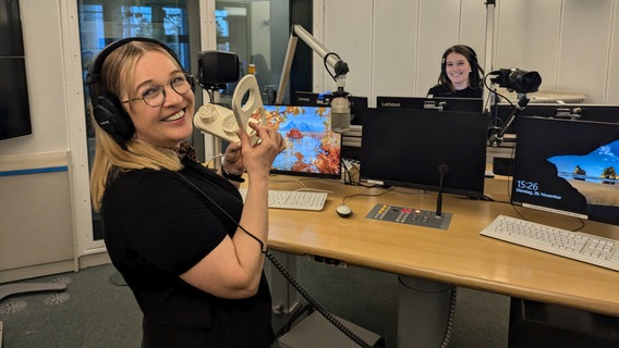 Geräuschemacherin Franziska Treutler steht mit einem Eierschneider in einem Radiostudio. © NDR Foto: Patrick Ortel