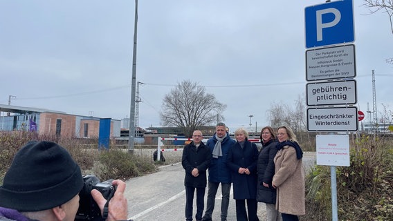 Ein Mann von hinten fotografiert eine Gruppe von Behördenmitarbeitern an einem Parkplatzschild. © Peter Schmidt Foto: Peter Schmidt