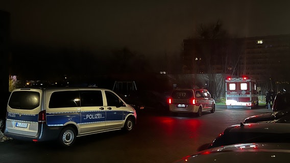 Ein Polizeiauto, ein Notarztwagen und ein Rettungswagen stehen bei Dunkelheit auf einem Parkplatz. Im Hintergrund ist ein Hochhaus zu sehen. © Felix Baenz Foto: Felix Baenz