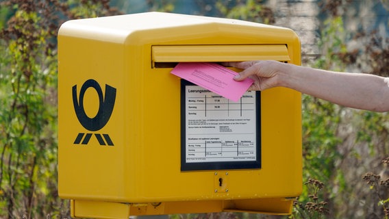 Eine Person wirft ihren Umschlag zur Briefwahl in einen Briefkasten. © dpa Foto: Peter Endig