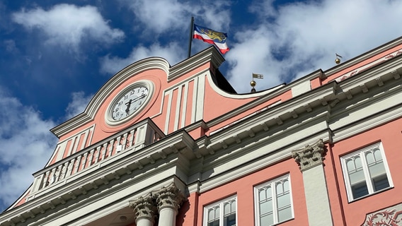 Die Fassade des Rostocker Rathauses, auf dem Dach weht die Flagge der Hansestadt. © NDR Foto: Christian Kohlhof