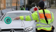 Bei einer Polizeikontrolle winkt eine Polizeibeamtin ein Fahrzeug heraus. © Bernd Wüstneck 