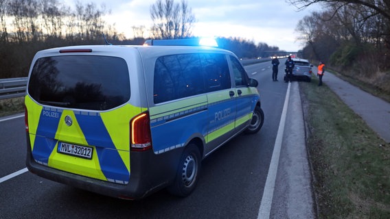 Ein Polizeifahrzeug steht in der Morgendämmerung auf einer Schnellstraße. Im Hintergrund stehen mehrere Personen an einem Fahrzeug am Seitenstreifen © Stefan Tretropp Foto: Stefan Tretropp