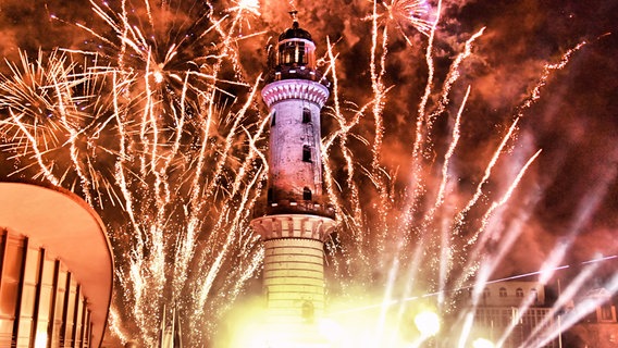 Hinter einem Leuchtturm steigt ein Feuerwerk in den Himmel von Warnemünde. © Tourismuszentrale Rostock & Warnemünde Foto: Joachim Kloock