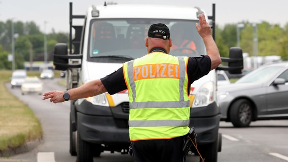 Ein Polizist steht während einer der landesweiten Polizeikontrollen unter dem Motto «Fahren.Ankommen.LEBEN!» an einer Straße, und winkt einen Fahrer an die Seite © picture alliance/dpa Foto: Bernd Wüstneck