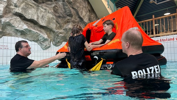 Kinder klettern in einem Schwimmbecken in eine aufblasbare Rettungsinsel. © Denis Mollenhauer Foto: Denis Mollenhauer