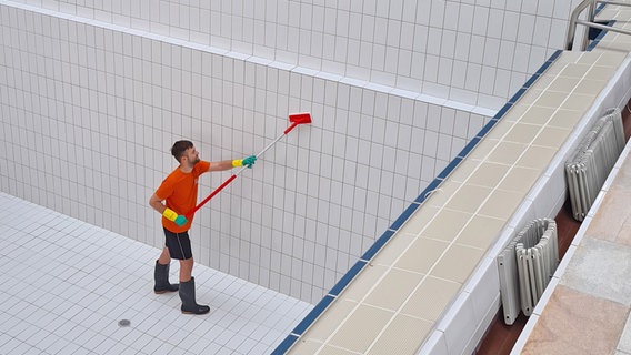 Ein Mitarbeiter reinigt die Wände des Schwimmbeckens © Stadtwerke Greifswald Foto: Stadtwerke Greifswald