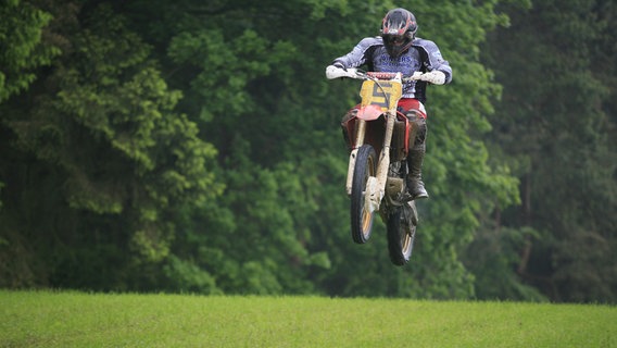 Ein Motorradfahrer springt beim traditionellen Bergring-Rennen an Pfingsten in Teterow mit seinem Zweirad in die Luft. (Themenbild) © picture-alliance Foto: Peter Frischmuth