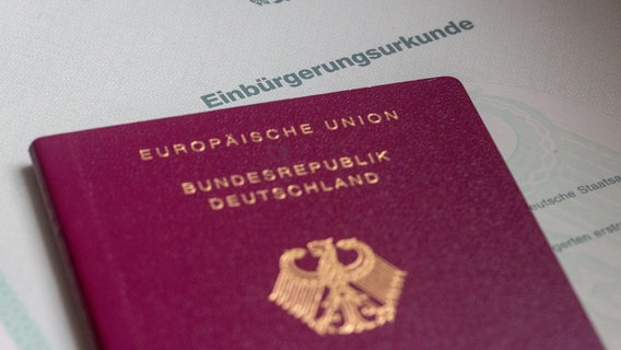 Eine Einbürgerungsurkunde der Bundesrepublik Deutschland und ein deutscher Reisepass liegen auf einem Tisch. © dpa-Bildfunk Foto: Fernando Gutierrez-Juarez