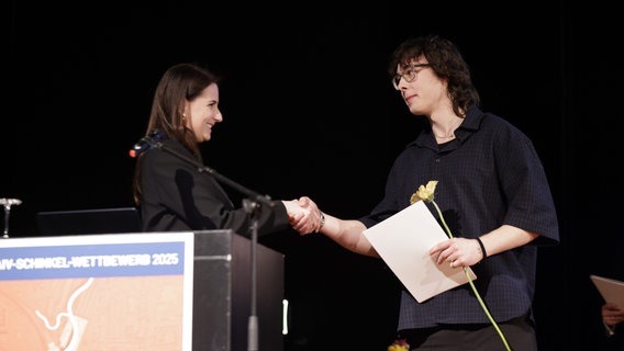 Eine Frau gratuliert einem Gewinner zu seinem Preis. © Pressestelle AIV-Schinkel-Wettbewerb Foto: Sebastian Gabsch