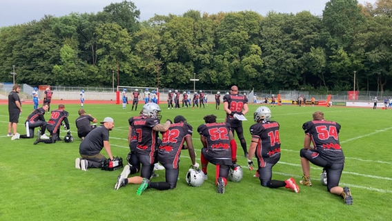 Ein paar Spieler der Greifswalder Footballmanschft stehen am Spielfeldrand. Im Hintergrund läuft das Spiel weiter. © Weronika Golletz Foto: Weronika Golletz