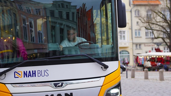 Ein weiß-gelber Bus des kommunalen Verkehrsbetriebes Nahbus. Der Fahrer rechnet einen Fahrgast ab. © NDR Foto: Christoph Woest