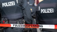 Polizisten stehen hinter einem Flatterband mit der Aufschrift "Polizeiabsperrung". © dpa Foto: Hannes P Albert