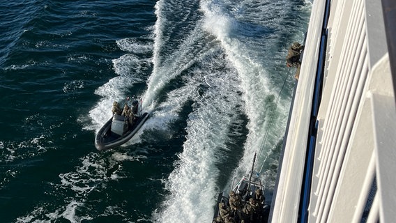 Polizisten gelangen mittels eines Seils am Schiffsrumpf auf das Deck. © Jürn-Jakob Gericke Foto: Jürn-Jakob Gericke