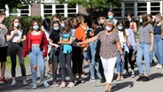 Am Innerstädtischen Gymnasium Rostock ISG gehen die Schüler der 9a nach ihrer Begrüßung mit Klassenleiterin Ines Gottwald mit Mund-Nasen-Schutz wieder ins Schulgebäude. © dpa-Bildfunk Foto: Bernd Wüstneck