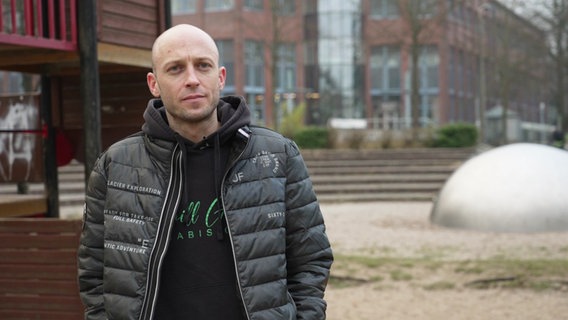 Marc Thalus, der in Greifswald einen Cannabis-Club eröffnen möchte, steht zwischen Technologie-Zentrum und Spielplatz. © Screenshot 