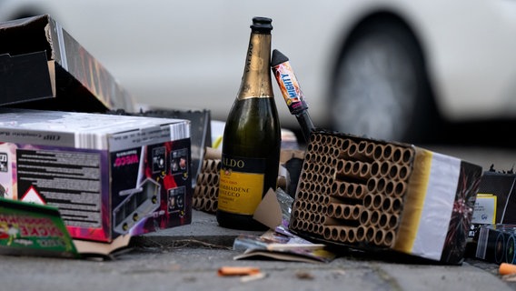 Eine Sektflasche und abgebrannte Feuerwerkskörper liegen nach der Silvesternacht auf einer Straße. © dpa Bildfunk Foto: Sven Hoppe/