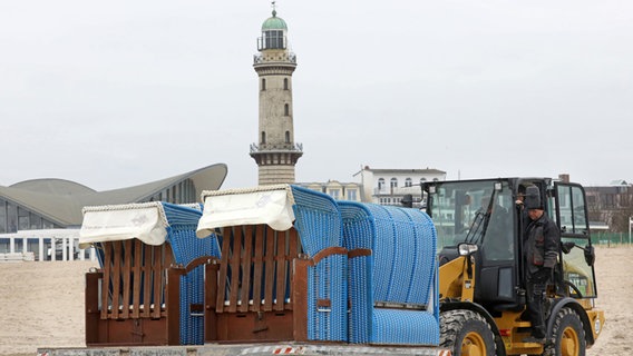 Mit einem Radlader werden Strandkörbe an den Strand gebracht, um sie aufzustellen. © dpa-Bildfunk Foto: Bernd Wüstneck, dpa