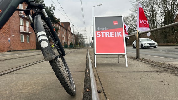 Ein Fahrrad steht quer auf Straßenbahnschienen nahe des Betriebshofs der Rostocker RSAG. Daneben steht ein Schild mit der Aufschrift "Heute Streik" © NDR Foto: Denis Mollenhauer