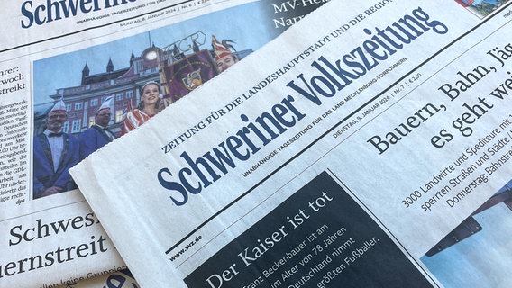 Mehrere Ausgaben der Schweriner Volkszeitung liegen aufeinander. Zuoberst liegt die die Ausgabe vom 9. Januar 2024 mit den Schlagzeilen "Der Kaiser ist tot" und "Bauern, Bahn, Jäger - es geht weiter". © NDR Foto: Thomas Potapski