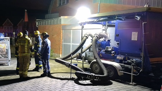 Eine Wasserpumpe auf einem THW-Anhänger. Dicke Schläuche führen in den Boden. © NDR Foto: Christoph Woest