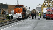 Rettungskräfte stehen im Rostocker Seehafen neben dem Wrack eines Transporters, der von einem Güterzug gerammt wurde. © Stefan Tretropp Foto: Stefan Tretropp