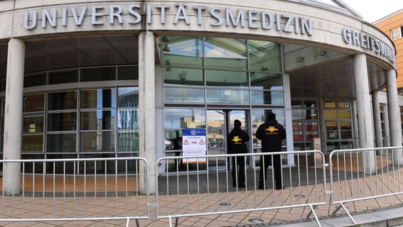 Sicherheistsleute stehen vor dem Hauptgebäude der Unimedizin Greifswald. © dpa Foto: Stefan Sauer