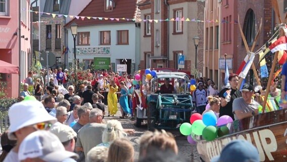 Bei einem Volksfest rollt ein geschmückter Traktor durch eine Menschenmenge. © NDR Foto: Thomas Eichler