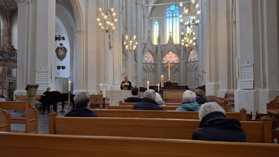 Menschen sitzen im Greifswalder Dom auf Kirchenbänken. © NDR Foto: Pierre Sens