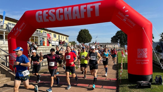 Freudige Gesichter bei etwa 30 Marathon Läuferinnen und Läufern als sie über die Ziellinie laufen © NDR Foto: Mathias Marius Krüger